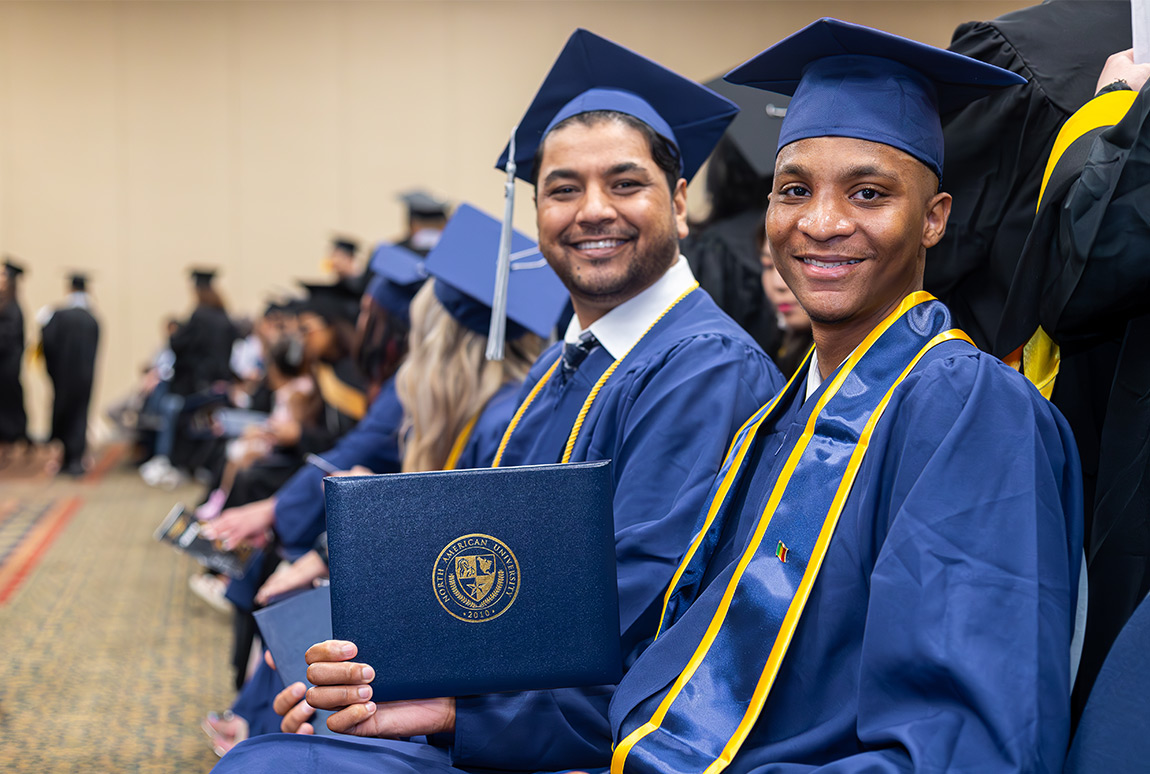 Two NAU students smiling with a diploma at commencement